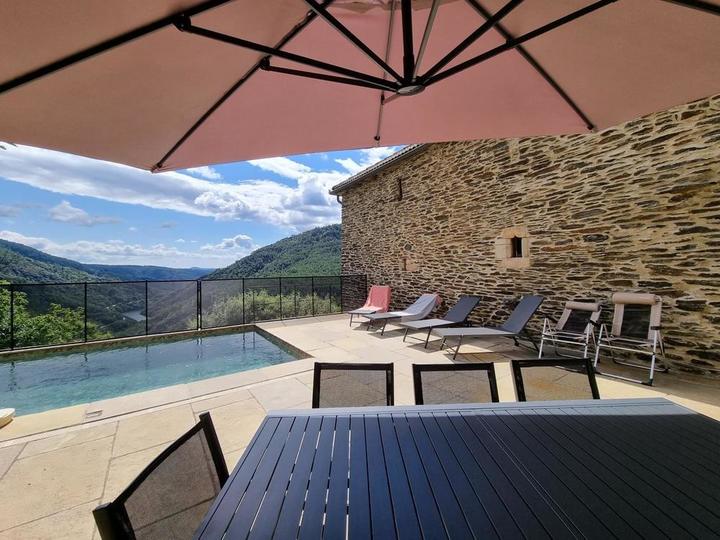 La terrasse, le salon de jardin avec le parasol déporté et les transats.