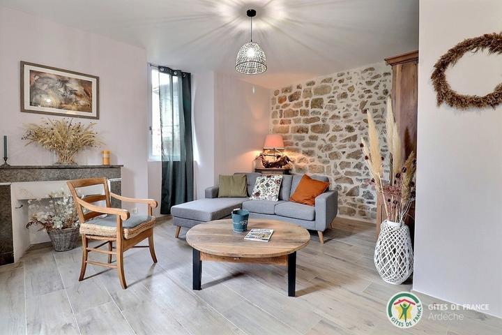 Salon avec mur en pierres apparentes, chaleureux avec canapé et TV