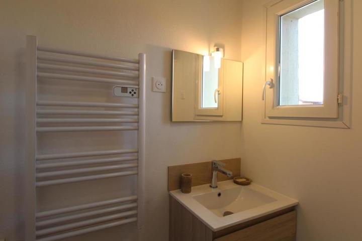 Salle d'eau avec meuble vasque de toilette et sèche serviettes.